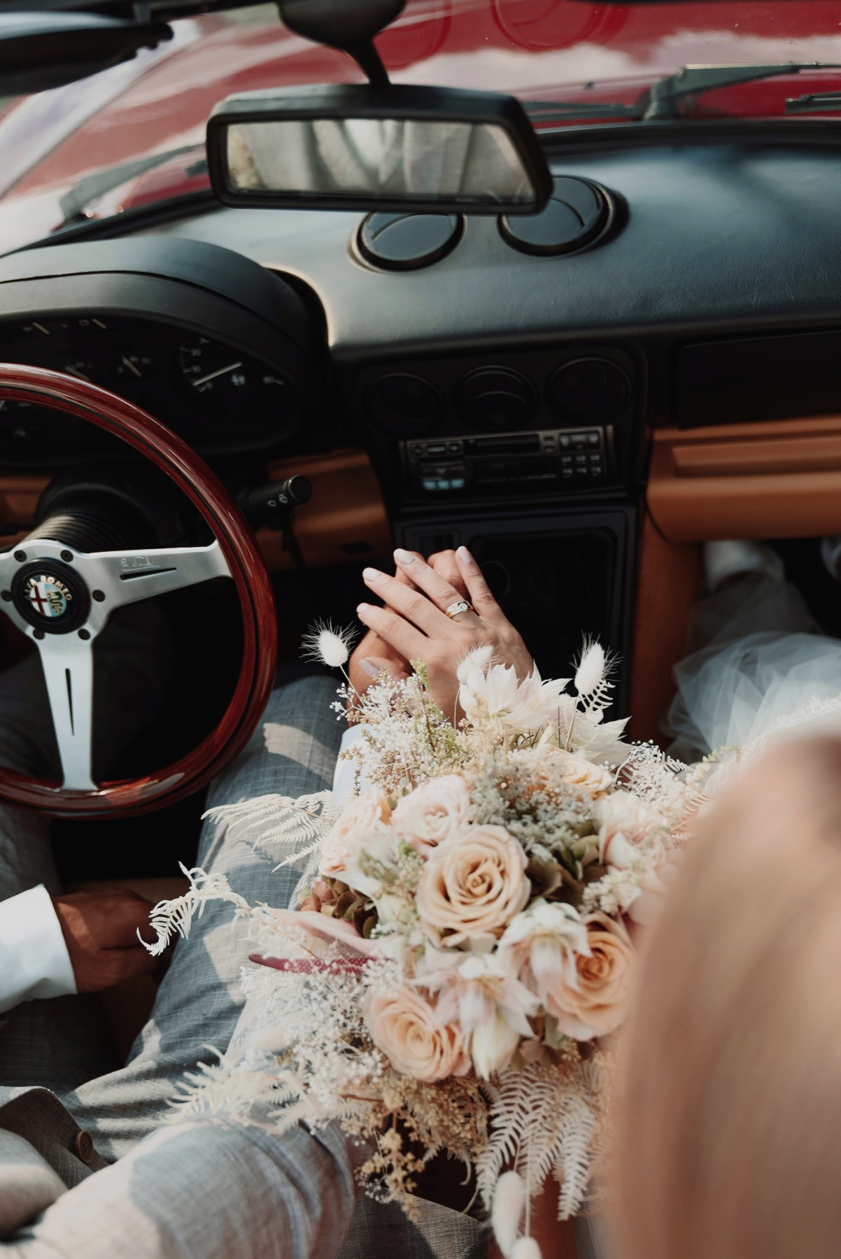 Casamento: mãos do casal e buquê no interior de um carro clássico: simulação de cores lavadas e contraste reduzido